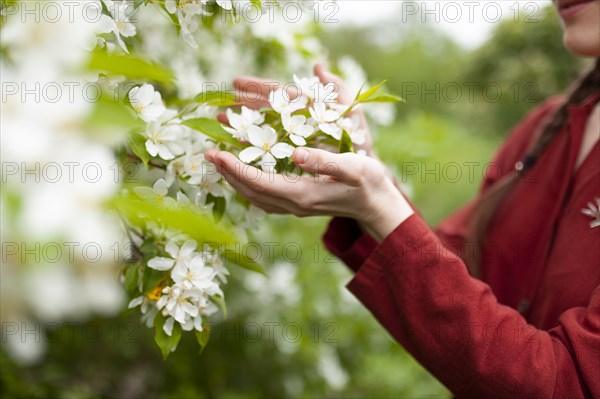 Young woman touching tree in blossom