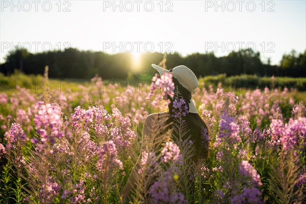 Rear view of woman standing in meadow on sunny day