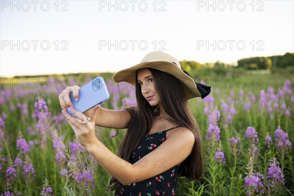 Young woman taking selfie while standing in meadow