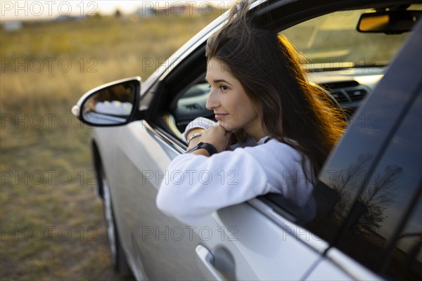 Young woman looking through window while driving car