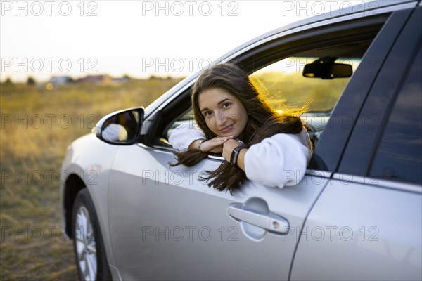 Portrait of young woman looking through car window