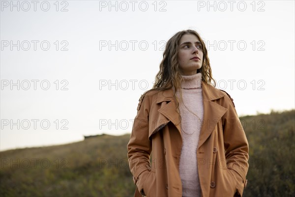 Portrait of serious woman looking away while standing in nature