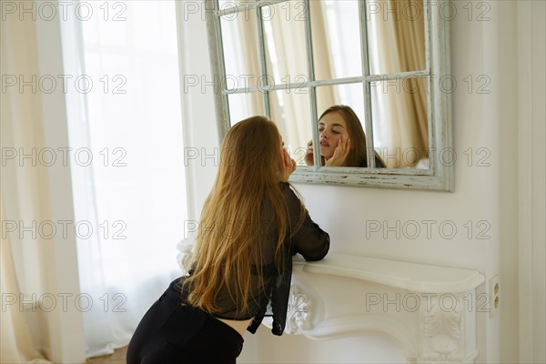 Young woman looking at mirror in apartment