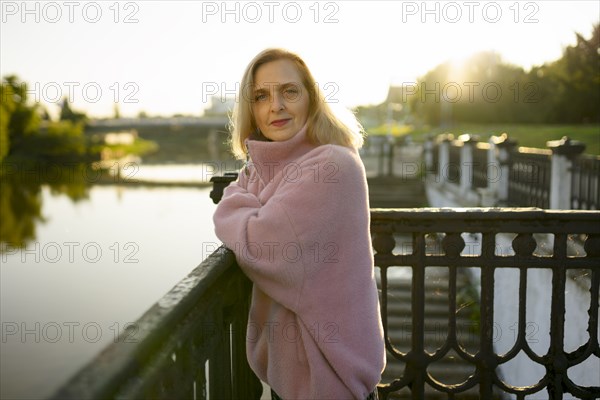 Portrait of mature woman standing by river at sunrise