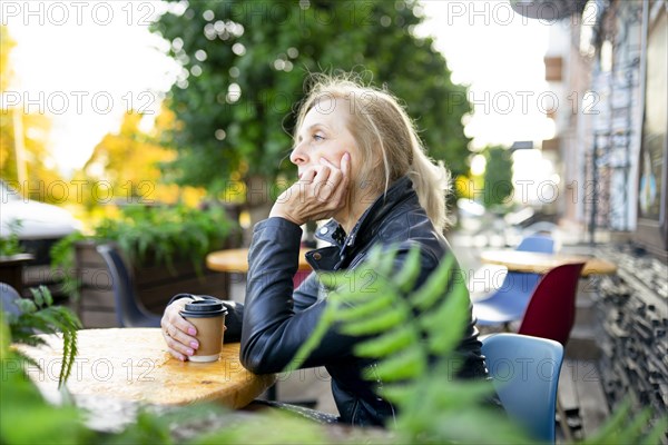 Thoughtful woman drinking coffee in sidewalk cafe