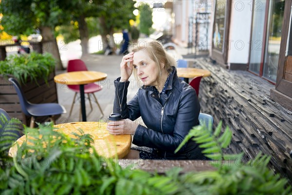 Thoughtful woman drinking coffee in sidewalk cafe