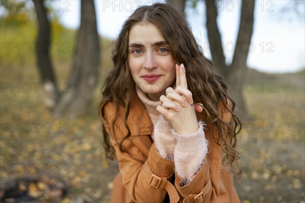 Portrait of smiling woman with hands clasped in park