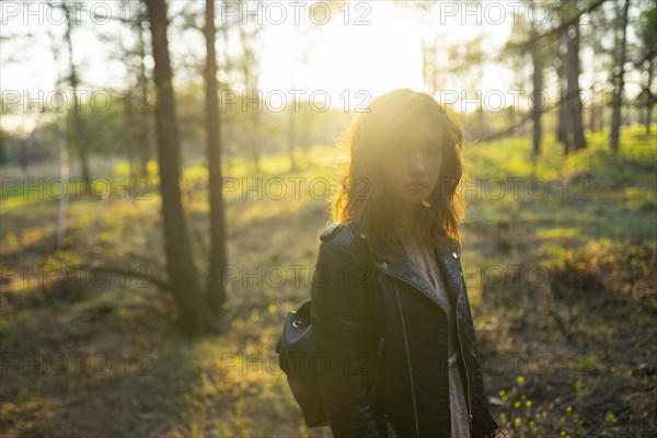 Portrait of woman standing in forest on sunny day