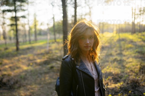 Portrait of woman standing in forest on sunny day