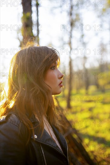 Side view of woman looking at forest on sunny day