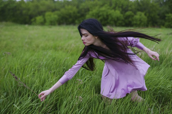 Portrait of young woman picking grass on meadow