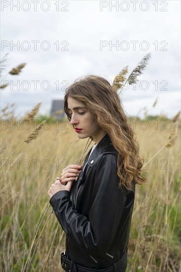 Portrait of woman standing in field on windy day