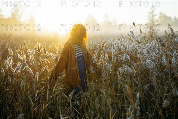Young woman walking in field at dawn