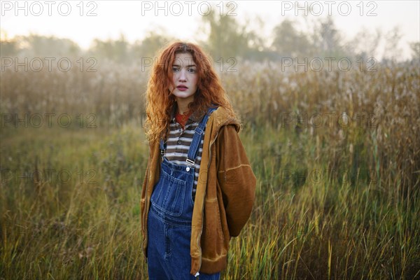 Portrait of young woman standing in field at dawn