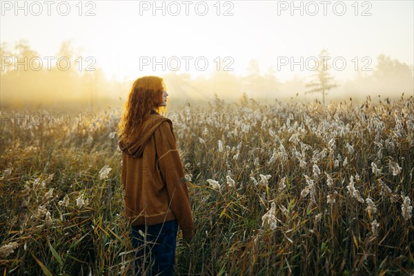 Rear view of woman standing in field at sunrise