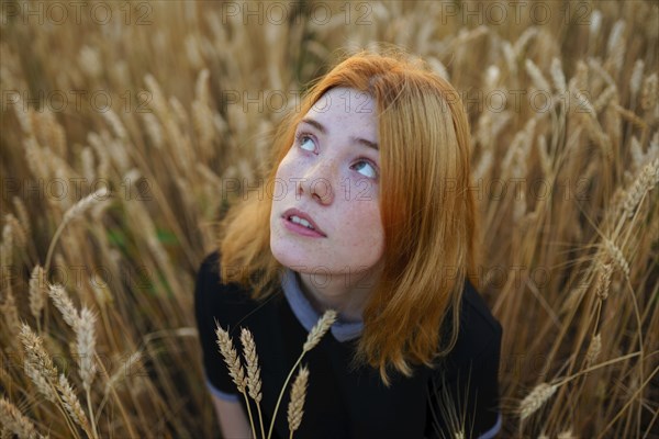 Thoughtful woman looking up while standing in agricultural field