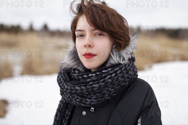 Portrait of serious woman looking at camera while standing in winter field