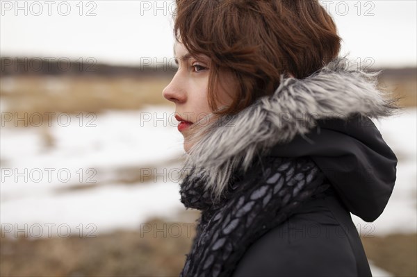 Portrait of thoughtful woman looking at field in winter scenery