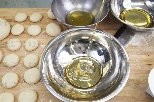 Olive oil pouring into bowl during bread baking