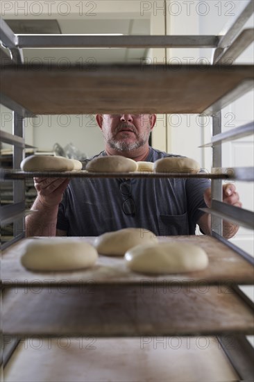 Baker standing with bread dough on tray