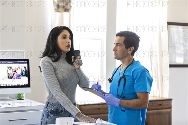 Nurse watching female patient blowing into breathalyzer machine