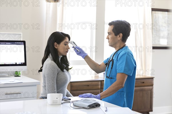 Nurse checking patient's temperature in examination room