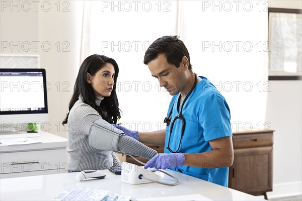 Nurse measuring blood pressure to female patient