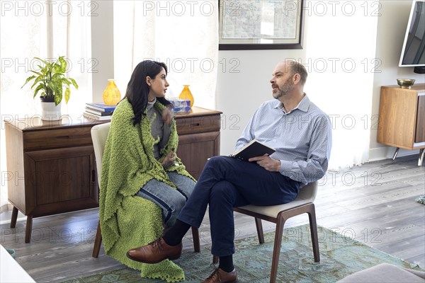 Female patient talking with man during psychotherapy at home