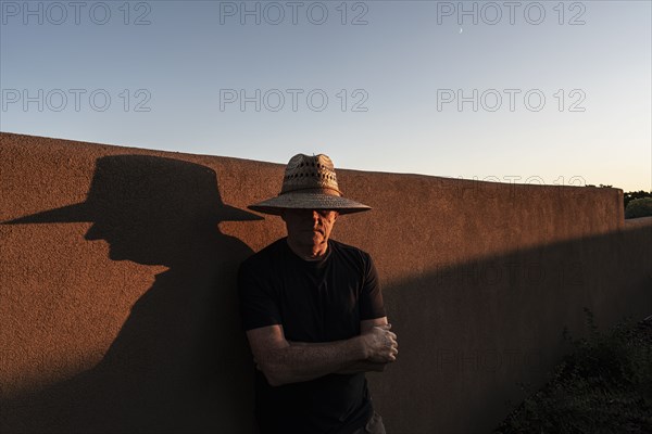 Usa, New Mexico, Santa Fe, Portrait of man in straw hat against adobe wall