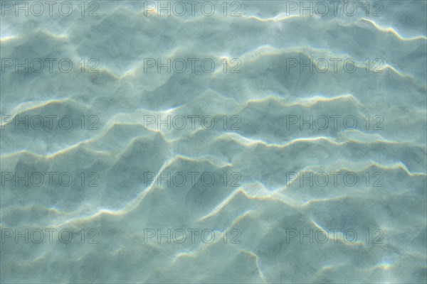 USA, United States Virgin Islands, St. John, Patterns in sand beneath light reflecting on water surface