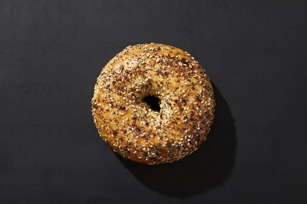 Overhead view of bagel with seeds on black background
