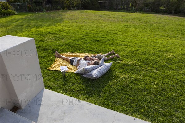 Mother and son lying on blanket in back yard