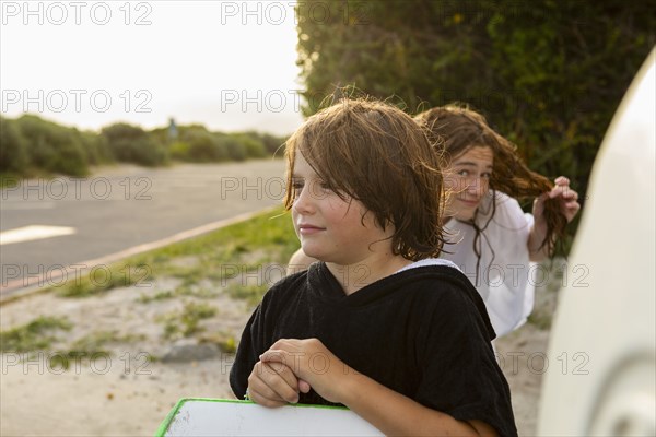 South Africa, Hermanus, Portrait of boy with surfboard and sister on beach