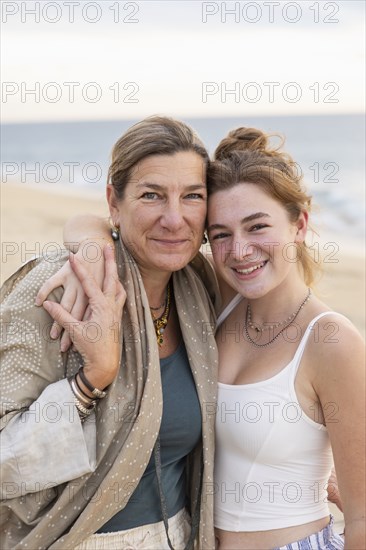 Portrait of smiling mother and teenage daughter on beach