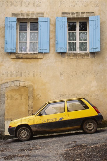 Yellow postal delivery vehicle parked outside a townhouse