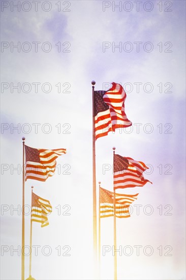American flags blowing on wind against sky at sunset