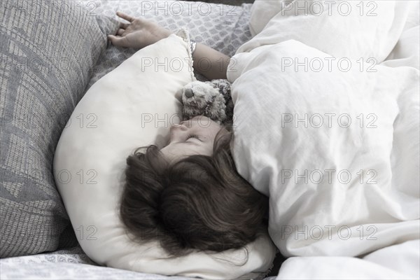 Overhead view of boy sleeping with stuffed toy in bed