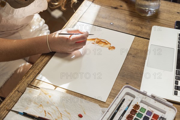 Close-up of teenage girl painting with watercolors at table