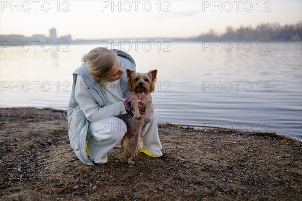 Woman with Yorkshire Terrier on lakeshore