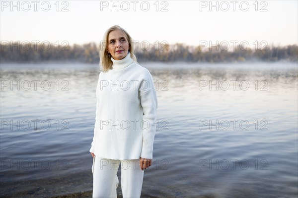 Portrait of woman in white sweater on lakeshore