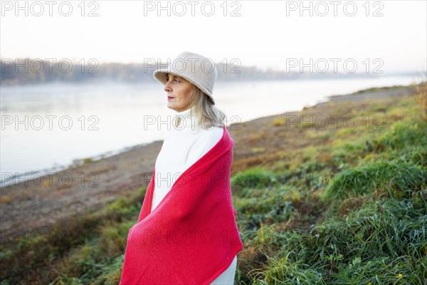 Portrait of woman wrapped in red shawl on lakeshore