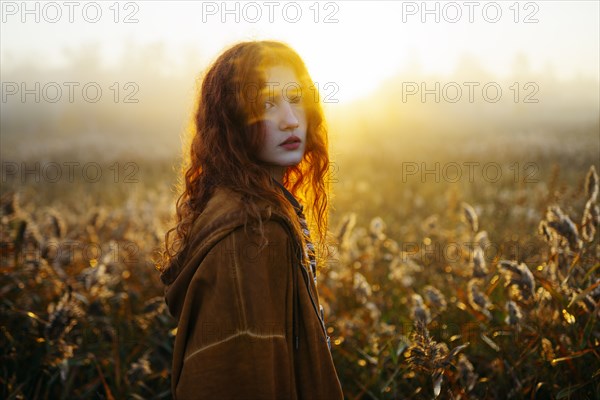 Portrait of redhead women in foggy field in autumn