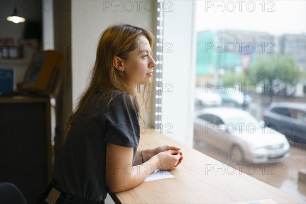 Woman leaning on window sill and looking through window
