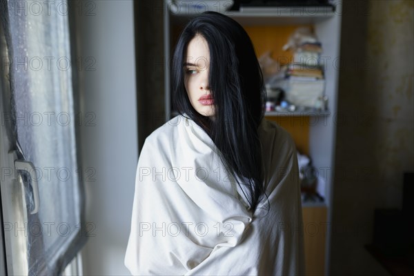 Portrait of pensive woman wrapped in white sheet