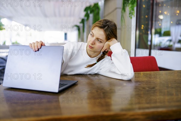 Woman looking at laptop at cafe table