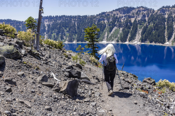 USA, Oregon, Rear view of woman hiking near calm Crater lake