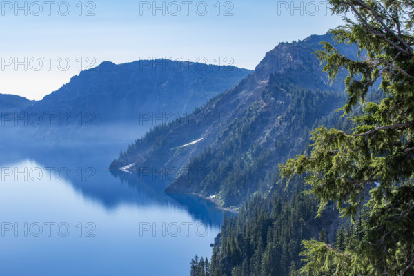 USA, Oregon, Hills reflected in calm, blue Crater lake