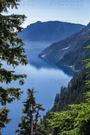 USA, Oregon, Hills reflected in calm, blue Crater lake