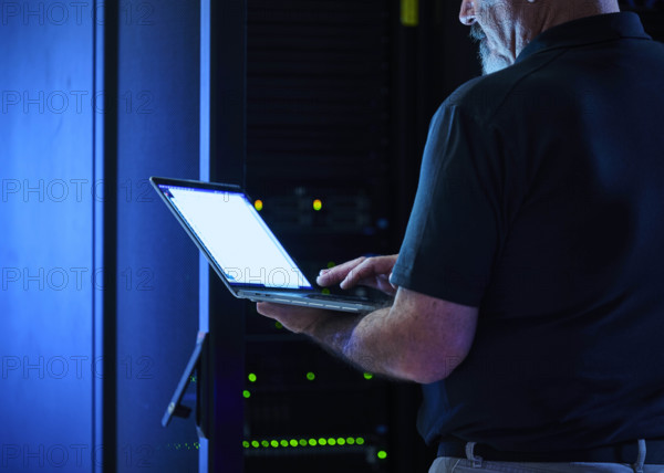 Close-up of man using laptop in data center