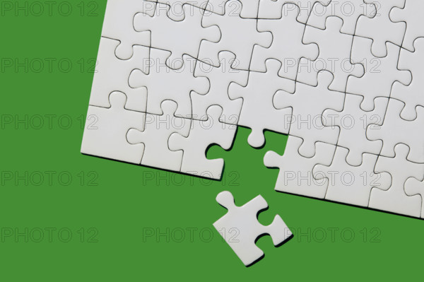 Studio shot of white puzzle pieces on green background